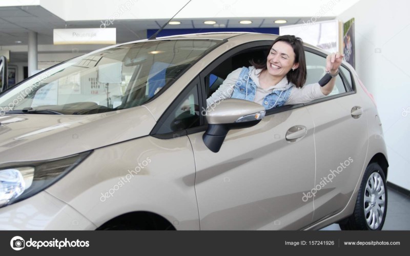 Happy woman showing the key of his new car. Auto business, car sale, technology and people concept - happy male with car dealer in auto show or salon